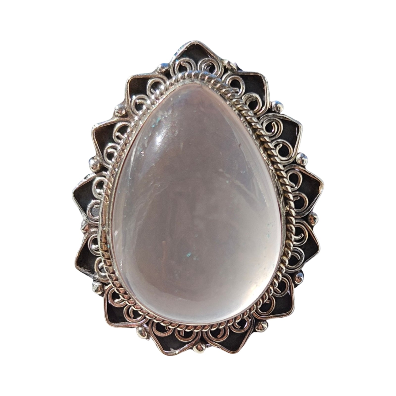 A teardrop-shaped silver ring featuring a smooth, pale Rose quartz cabochon gemstone in the center, surrounded by an ornate filigree silver border with dark inlay details